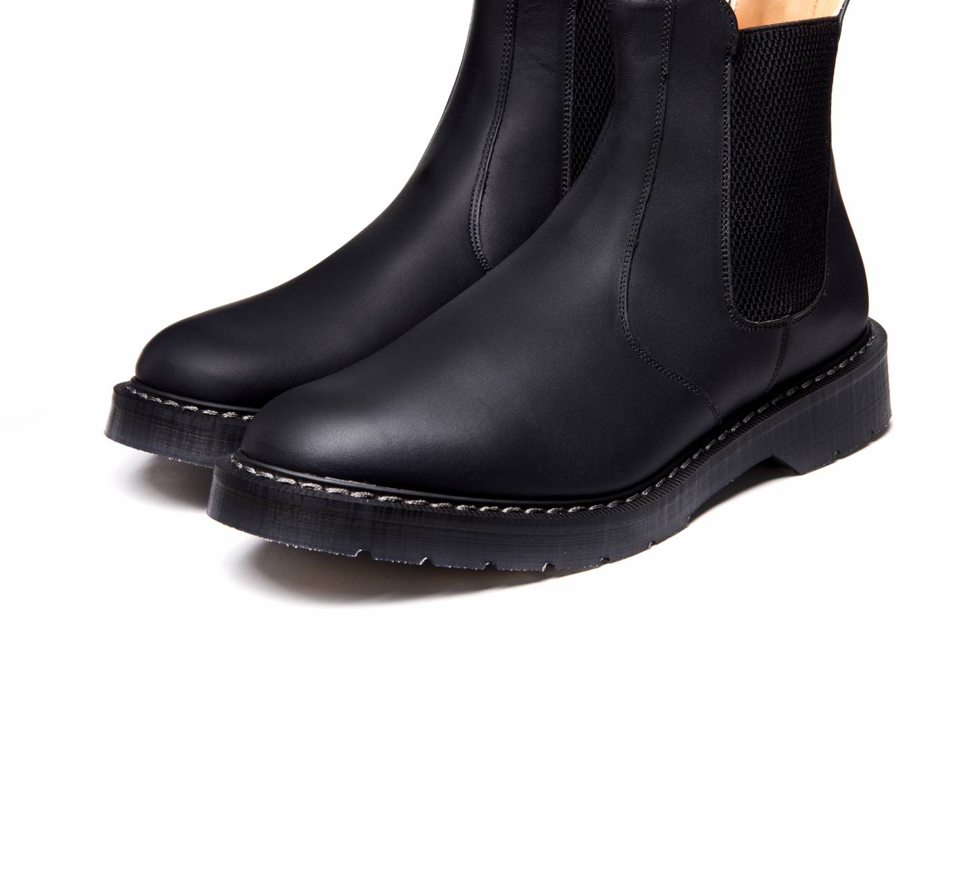 black leather Chelsea boot with elastic sides and goodyear welted rubber sole with visible grey stitching similar to classic Dr. Martens boots; ankle-high