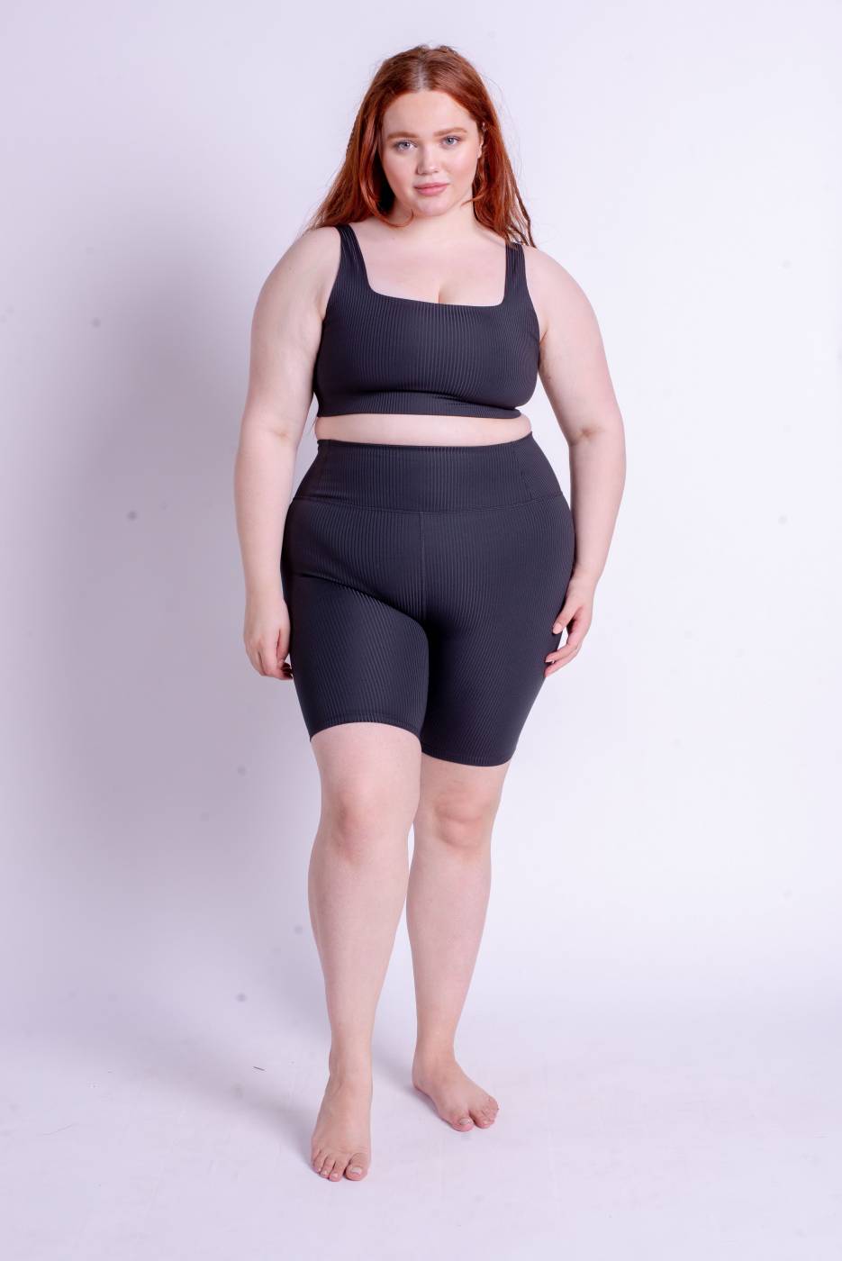 Frau trägt Sport Top und gerippte Radlerhose in schwarz aus recycelten Materialien
